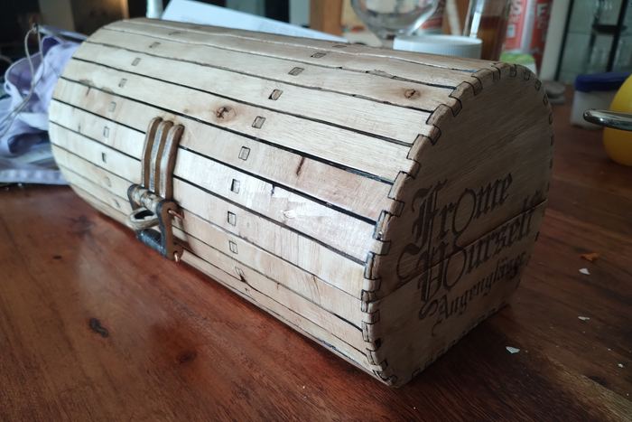 Ein Holzstamm mit eingravierter Schrift liegt auf einer Werkbank